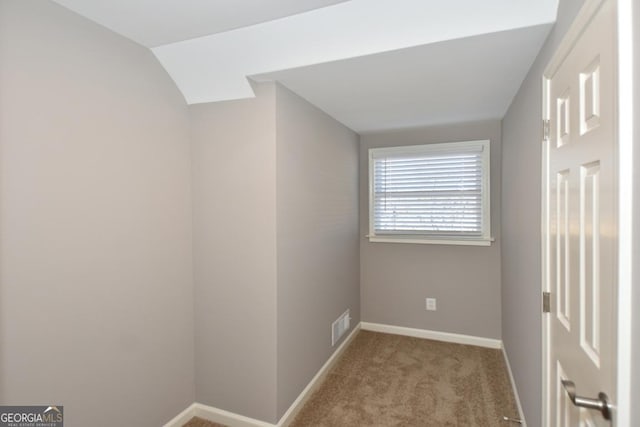 empty room with light colored carpet and vaulted ceiling