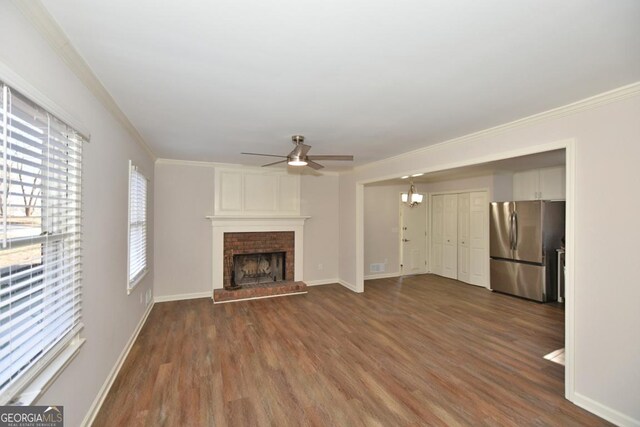 unfurnished living room with a brick fireplace, a wealth of natural light, ceiling fan, dark wood-type flooring, and crown molding