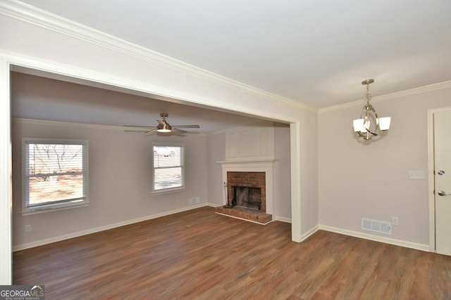 unfurnished living room featuring a fireplace, dark hardwood / wood-style flooring, ceiling fan with notable chandelier, and crown molding