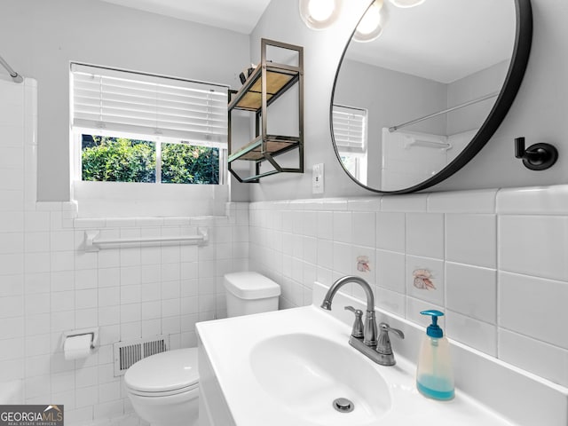 bathroom with a shower, toilet, tile walls, and sink