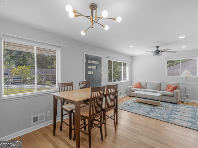 dining room with ceiling fan with notable chandelier and light wood-type flooring