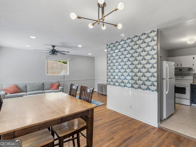 dining area featuring ceiling fan with notable chandelier and light hardwood / wood-style flooring