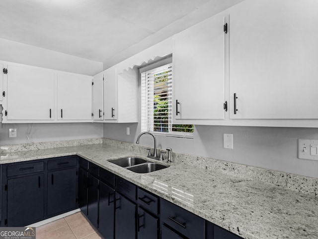 kitchen featuring white cabinets, light tile patterned floors, light stone counters, and sink