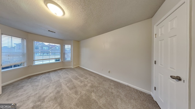 carpeted empty room with a textured ceiling