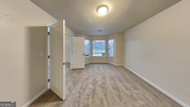 spare room with light carpet and a textured ceiling