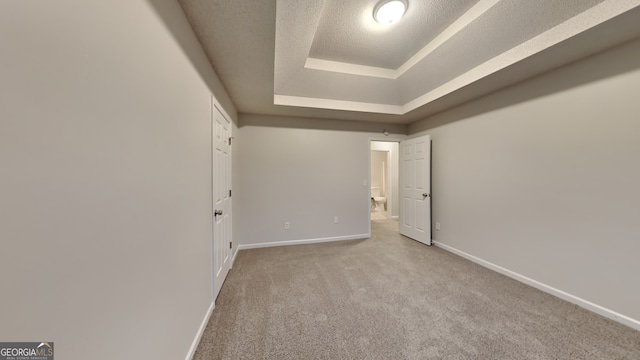 carpeted empty room with a raised ceiling and a textured ceiling