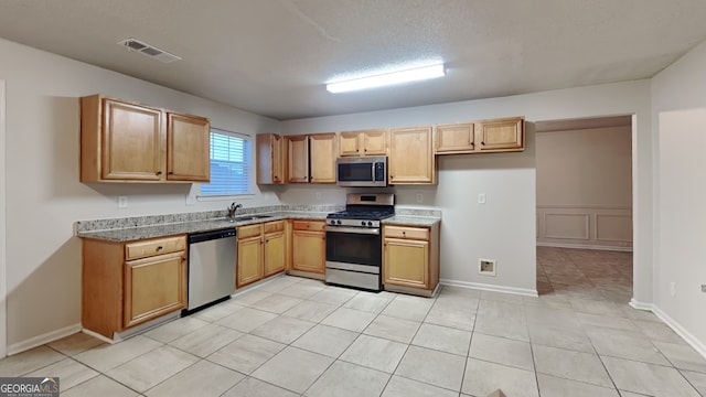 kitchen featuring light tile patterned floors, a textured ceiling, stainless steel appliances, and sink