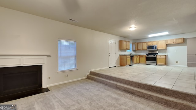 kitchen featuring light brown cabinets, light colored carpet, stainless steel appliances, and sink