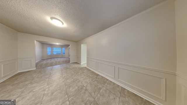 tiled empty room with a textured ceiling and crown molding