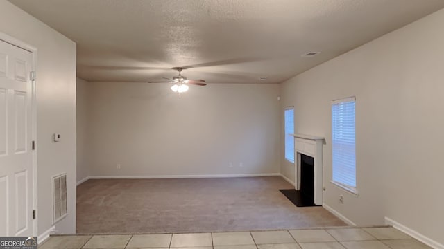 unfurnished living room featuring ceiling fan, light tile patterned floors, and a textured ceiling