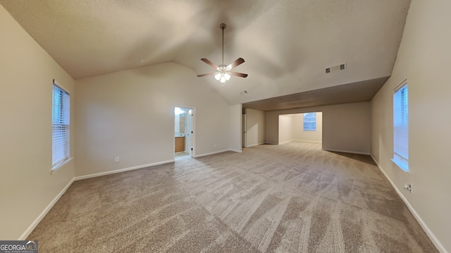 unfurnished living room featuring ceiling fan, light colored carpet, and vaulted ceiling