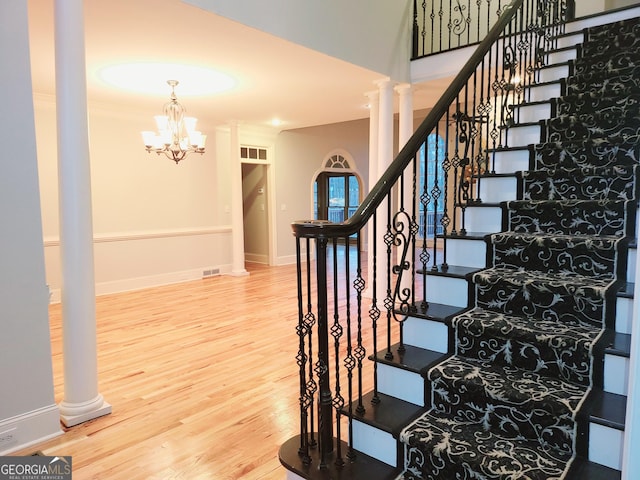 staircase featuring a chandelier, hardwood / wood-style flooring, and crown molding