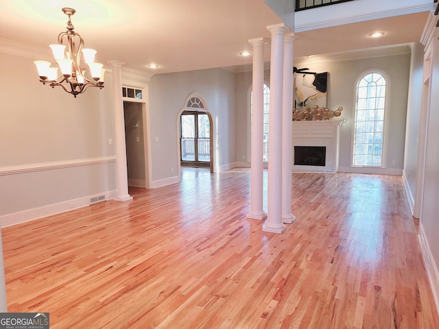 unfurnished living room featuring light wood-type flooring, ornamental molding, and a chandelier