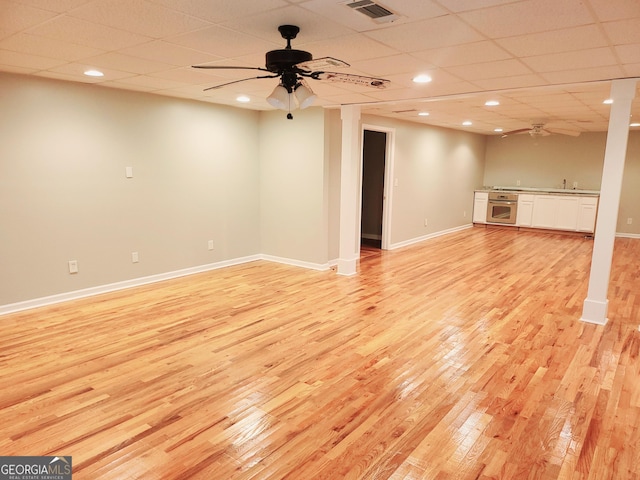 basement featuring a paneled ceiling, sink, and light hardwood / wood-style floors