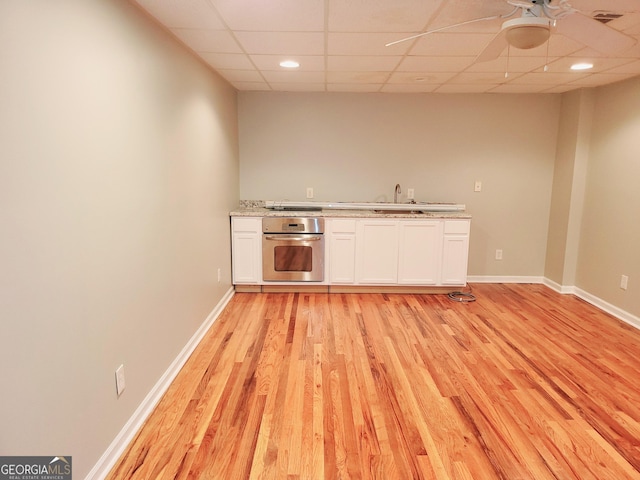 kitchen with white cabinetry, sink, a drop ceiling, stainless steel appliances, and light hardwood / wood-style floors