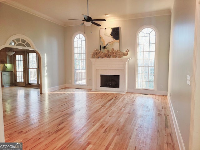 unfurnished living room with ceiling fan, light wood-type flooring, and ornamental molding