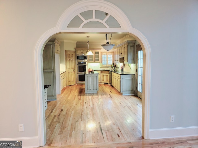 kitchen featuring stainless steel appliances, crown molding, pendant lighting, decorative backsplash, and light wood-type flooring