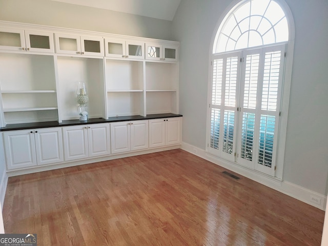 spare room with lofted ceiling and light hardwood / wood-style flooring