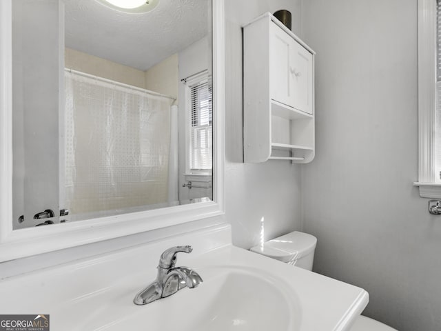 bathroom featuring sink, toilet, a textured ceiling, and a shower with shower curtain