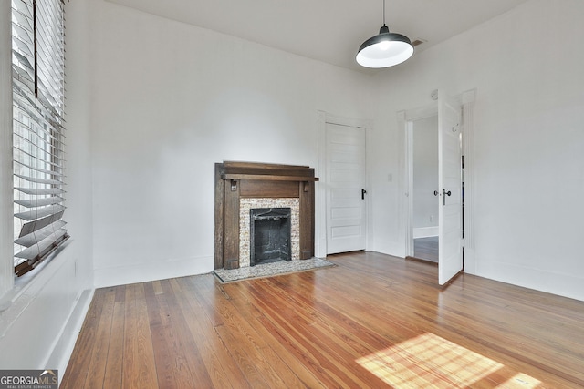 unfurnished living room featuring hardwood / wood-style flooring and a stone fireplace