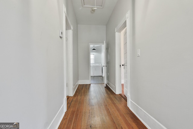 hallway with separate washer and dryer and hardwood / wood-style flooring