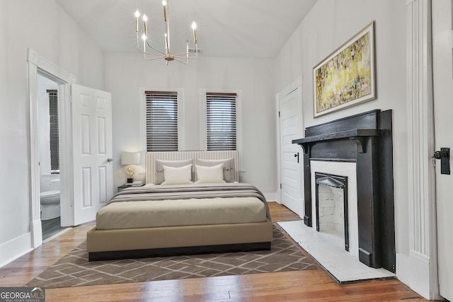 bedroom with dark hardwood / wood-style floors, a notable chandelier, and ensuite bathroom