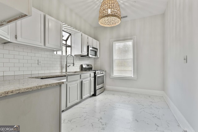 kitchen featuring light stone counters, stainless steel appliances, white cabinetry, and sink