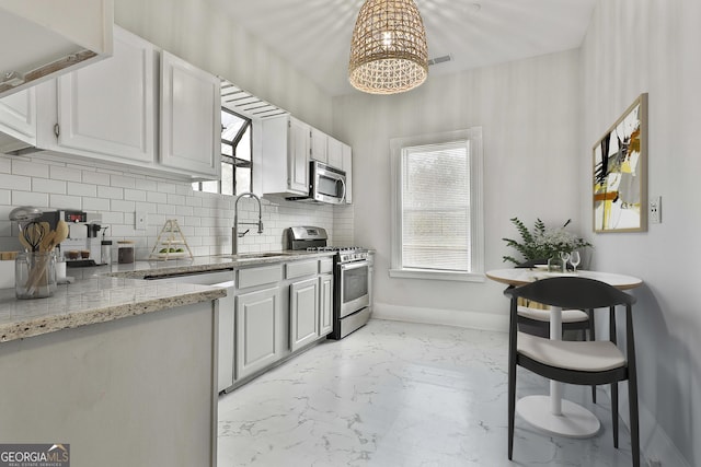 kitchen featuring white cabinetry, sink, light stone countertops, and appliances with stainless steel finishes