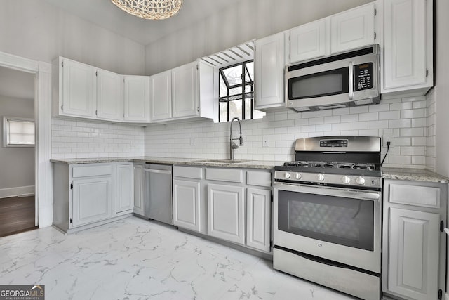 kitchen with light stone countertops, sink, decorative backsplash, white cabinets, and appliances with stainless steel finishes