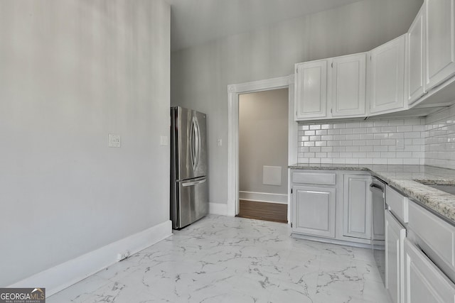 kitchen featuring light stone countertops, white cabinetry, appliances with stainless steel finishes, and tasteful backsplash