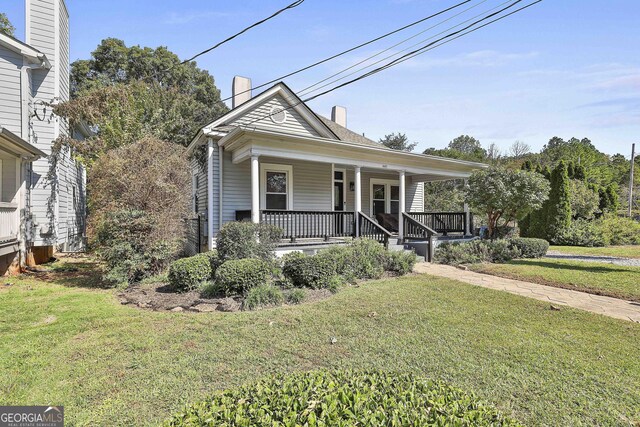 bungalow featuring covered porch and a front yard