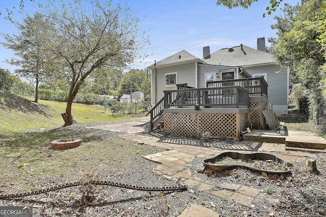 rear view of house with a deck and an outdoor fire pit