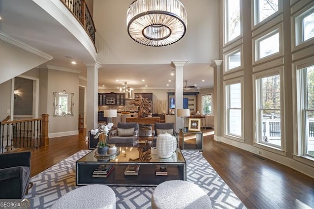 living room with crown molding, dark hardwood / wood-style flooring, a high ceiling, and ornate columns