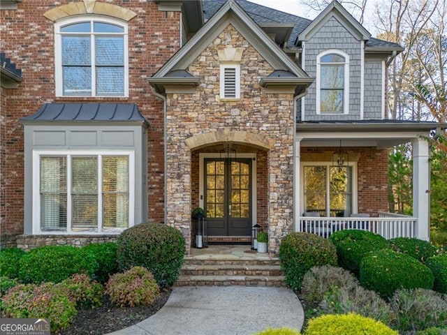 view of exterior entry featuring french doors and a porch