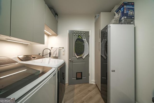 laundry room featuring independent washer and dryer and light hardwood / wood-style flooring