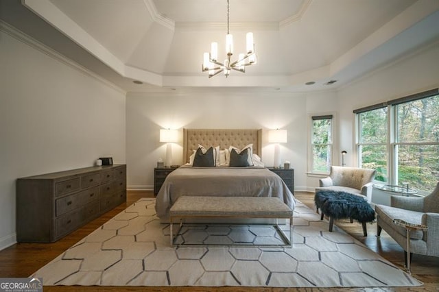 bedroom featuring an inviting chandelier, hardwood / wood-style floors, a tray ceiling, and ornamental molding