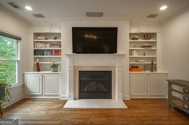 living room with ornamental molding, dark wood-type flooring, and built in features