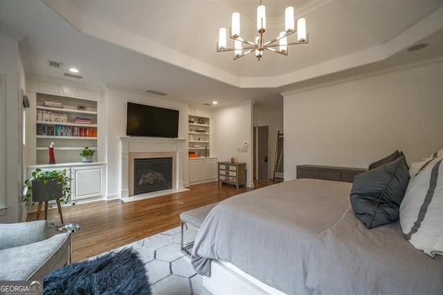 bedroom with a raised ceiling, ornamental molding, and an inviting chandelier