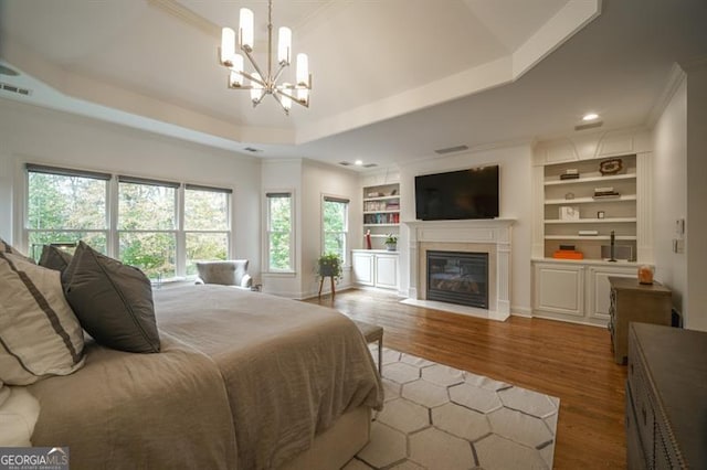 bedroom with an inviting chandelier, a raised ceiling, and multiple windows