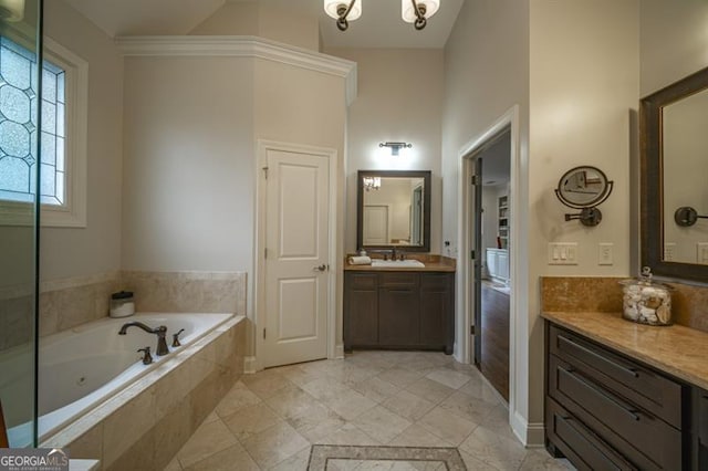 bathroom featuring an inviting chandelier, vanity, and tiled tub