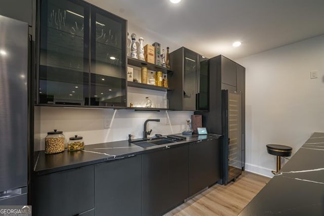 kitchen with sink, stainless steel fridge, and light wood-type flooring