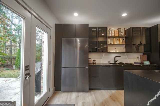 kitchen featuring stainless steel refrigerator, sink, light hardwood / wood-style floors, dark brown cabinets, and french doors