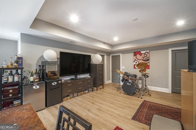 living room featuring bar, a raised ceiling, and light wood-type flooring