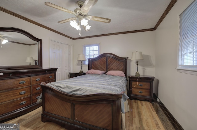 bedroom featuring ceiling fan, light wood-type flooring, ornamental molding, and a closet