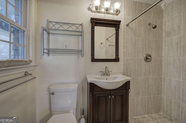 bathroom featuring a tile shower, vanity, and toilet