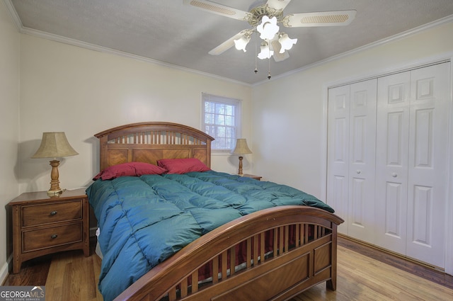 bedroom with ornamental molding, a textured ceiling, ceiling fan, light hardwood / wood-style flooring, and a closet