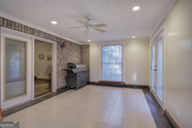 interior space featuring light tile patterned floors, ceiling fan, crown molding, and brick wall