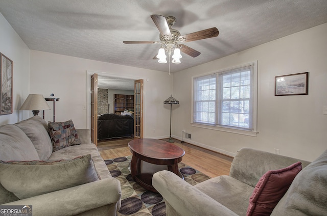 living room featuring a textured ceiling, hardwood / wood-style flooring, and ceiling fan