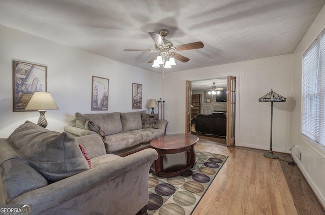 living room featuring a wealth of natural light, ceiling fan, a textured ceiling, and light wood-type flooring