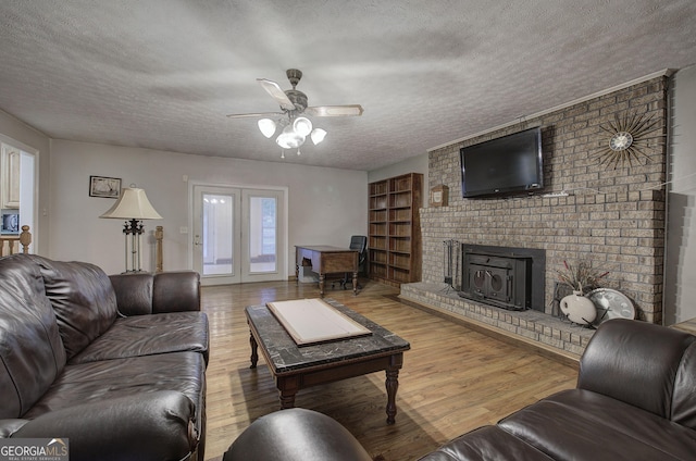 living room featuring hardwood / wood-style floors, a textured ceiling, a wood stove, and ceiling fan